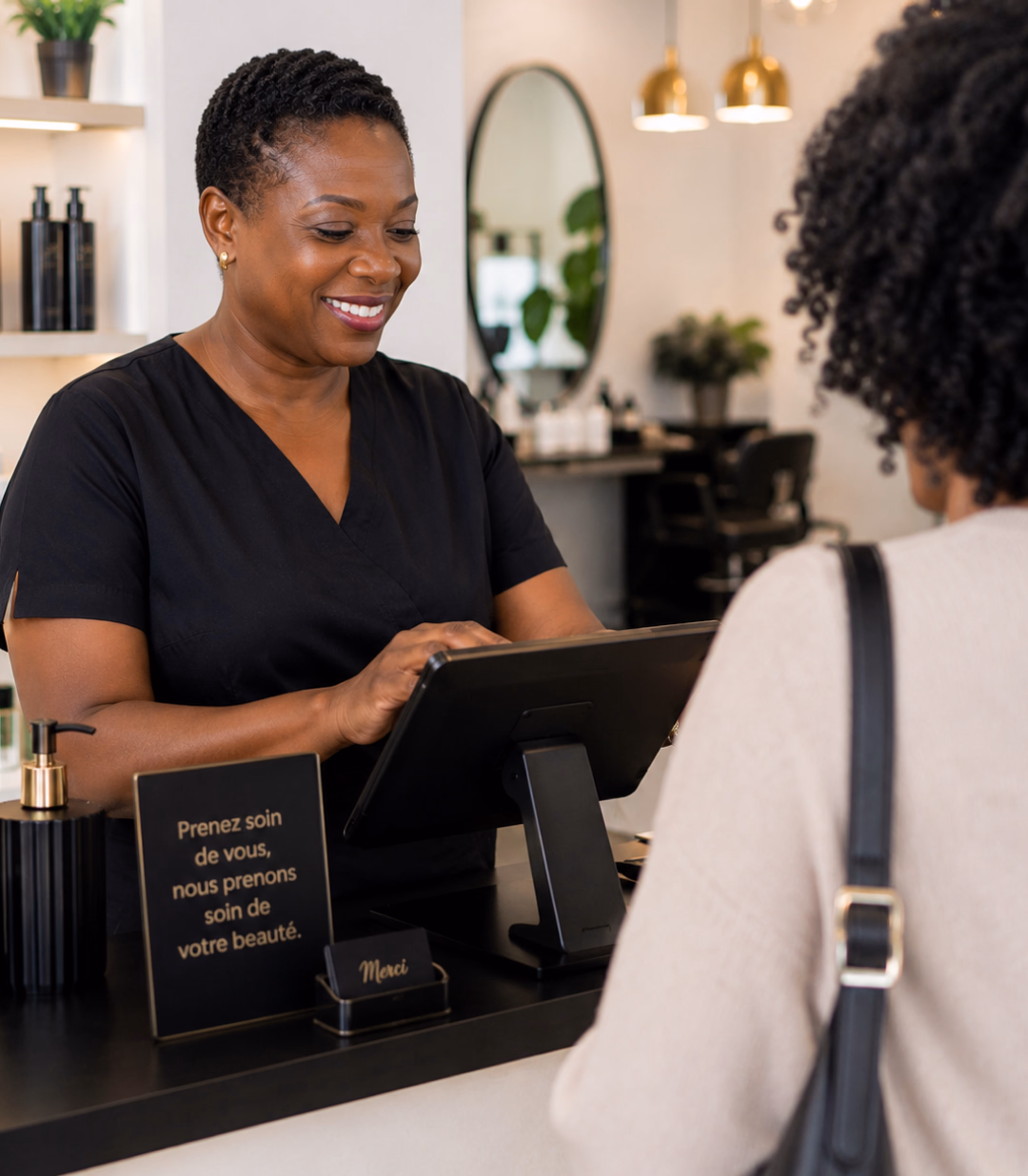 Esthéticienne souriante au comptoir de son institut avec la tablette de caisse Sliderz